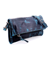 The Amina by Bed Stu is a sleek black and teal leather clutch bag featuring a front zipper, a buckled strap, and the versatility to double as a stylish crossbody.