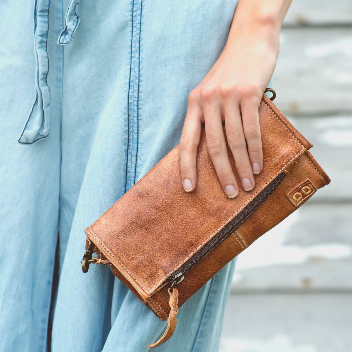 A woman is holding an Amina brown leather wallet by Bed Stu.