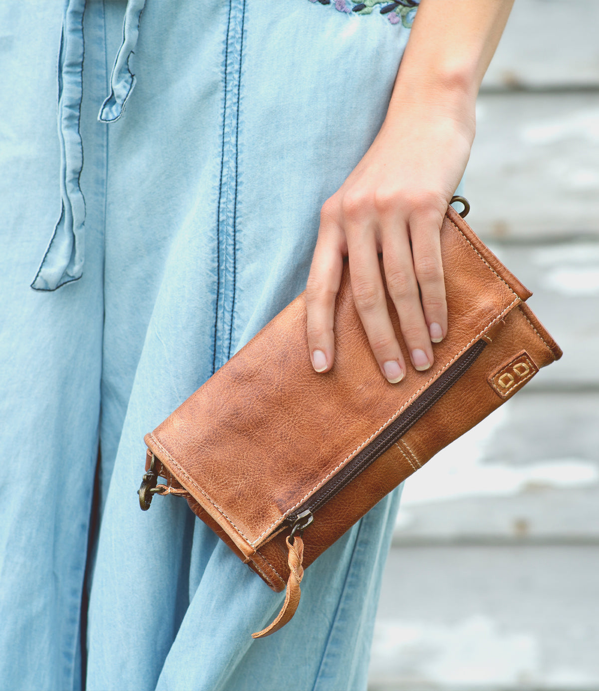 A woman is holding an Amina brown leather wallet by Bed Stu.