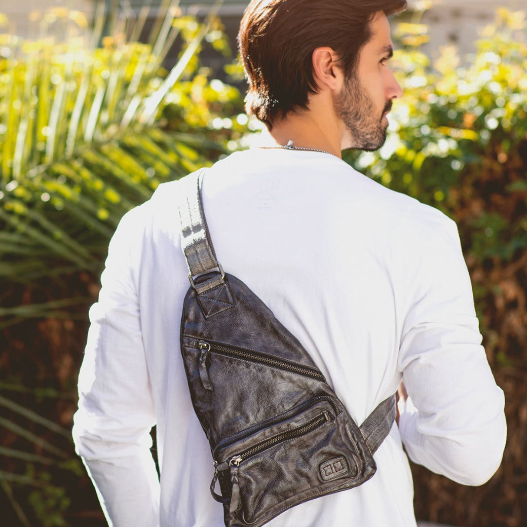 A man wearing a black leather Andie sling bag from Bed Stu.