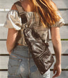 A woman wearing ripped jeans and a Bed Stu Andie leather sling bag.