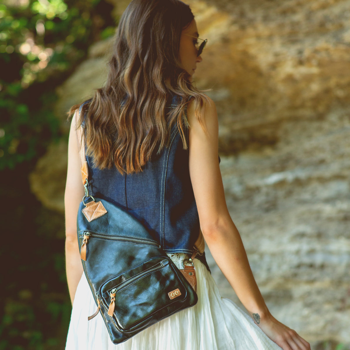 A woman wearing a white dress and a black Bed Stu Andie sling bag.