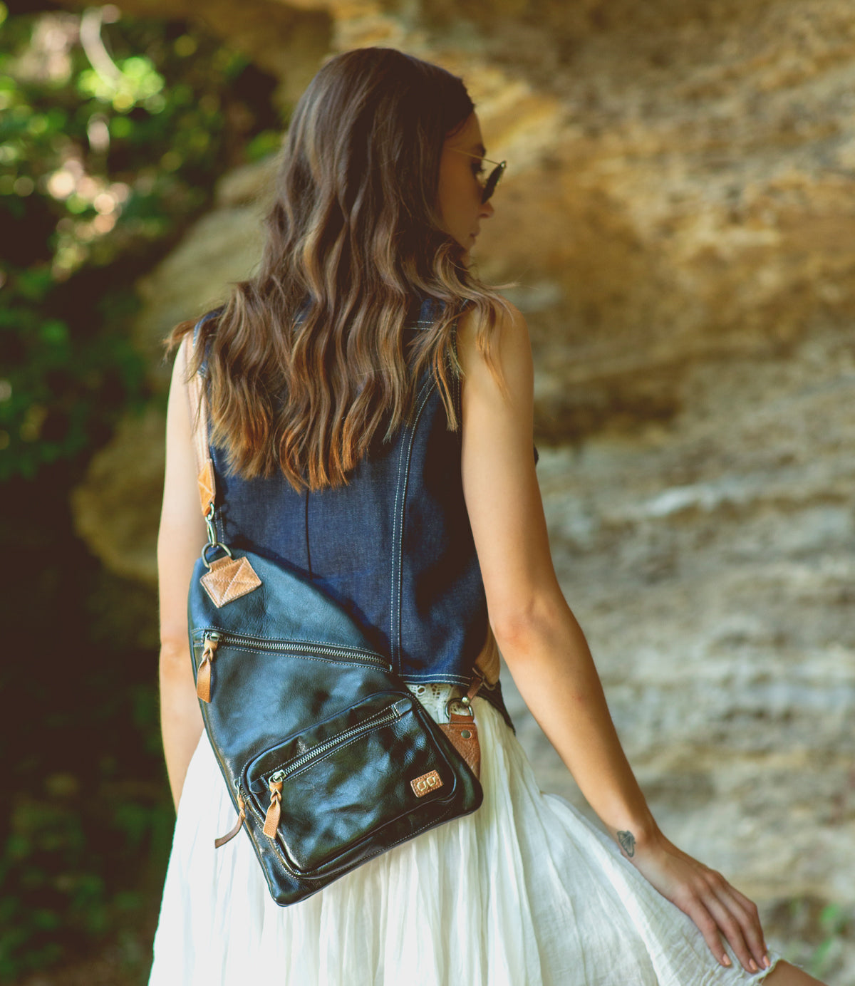 A woman wearing a white dress and a black Bed Stu Andie sling bag.