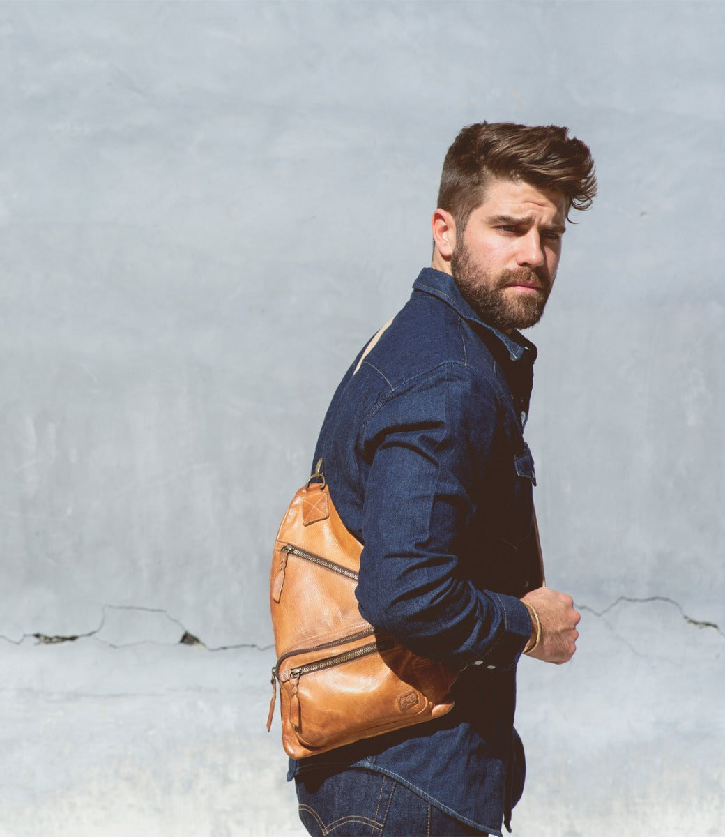 A man with a beard carrying an Andie tan leather sling bag by Bed Stu.