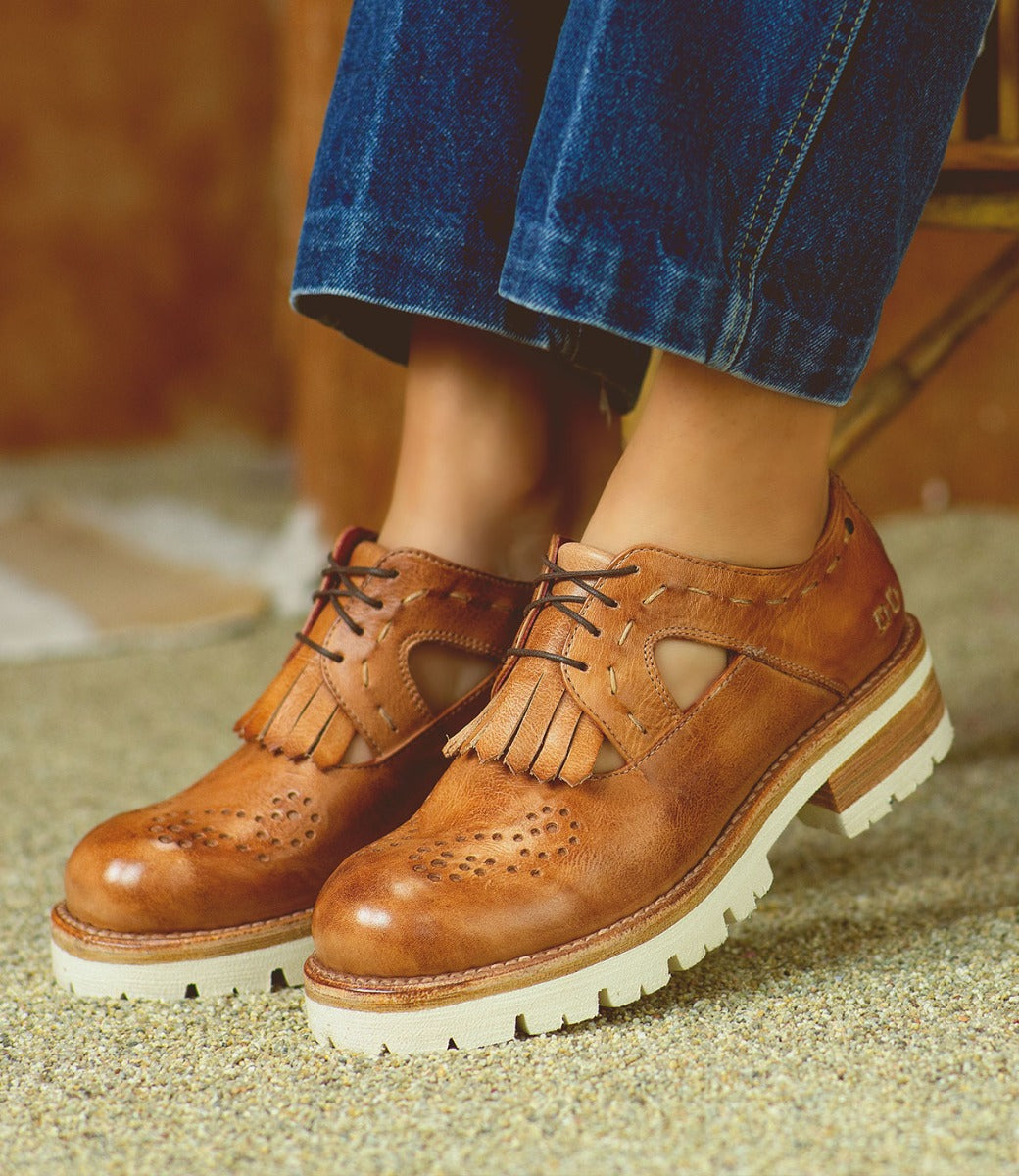 A woman wearing a pair of brown Bed Stu Anise oxford shoes.