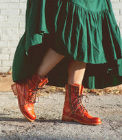 A woman wearing an Anne green dress and Bed Stu boots.