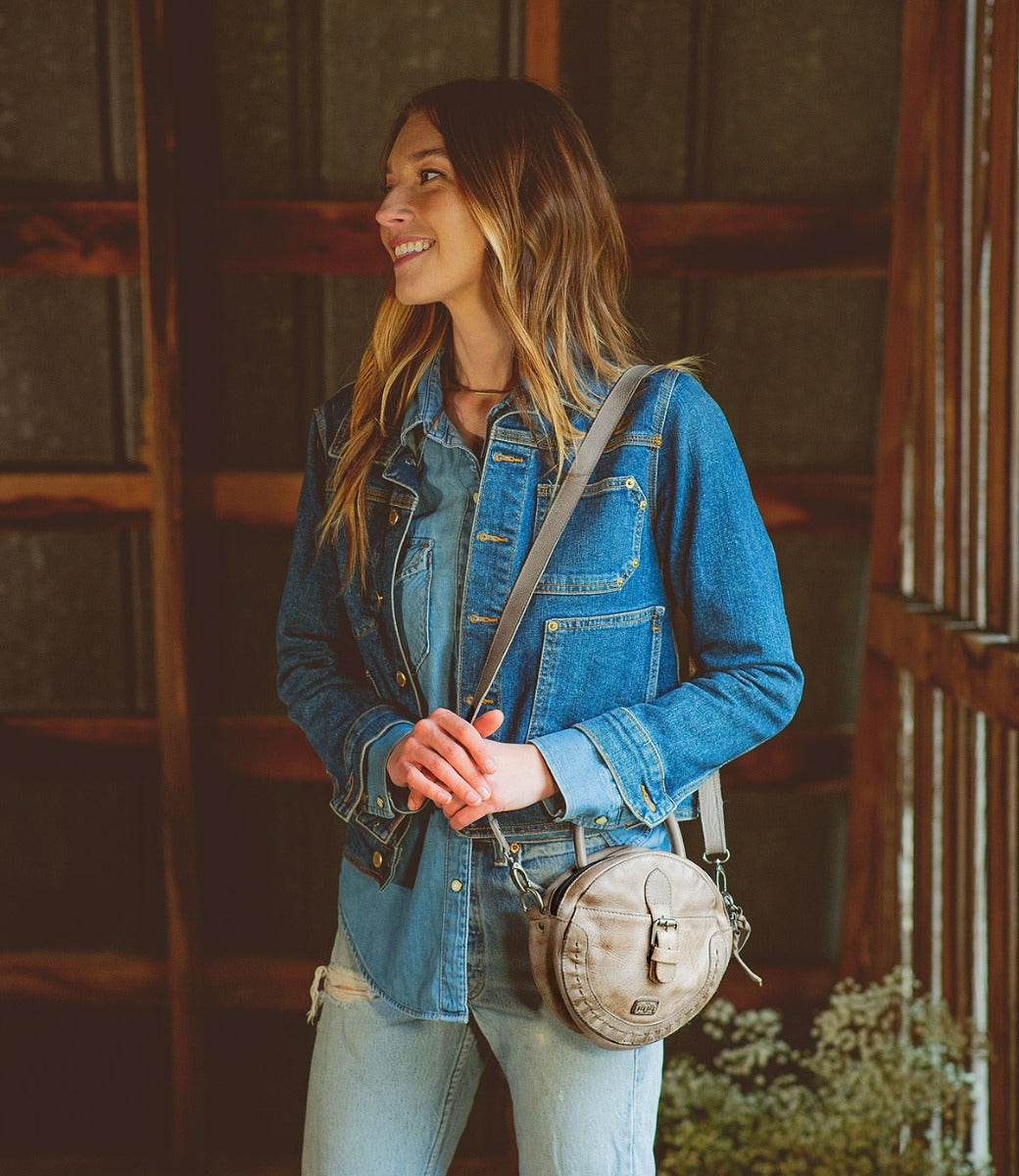 A women holding a Bed Stu Arenfield bag with a strap and buckle, made by Bed Stu.