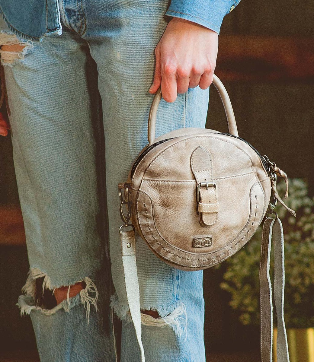 A woman is holding an Arenfield purse made by Bed Stu.