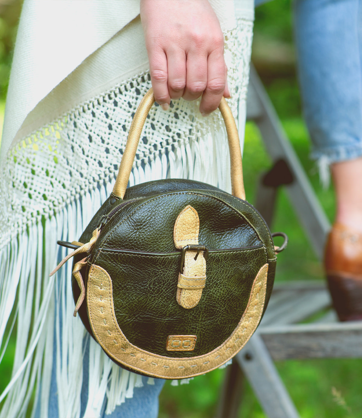 A woman holding a Bed Stu handbag with tassels and fringes, called Arenfield.