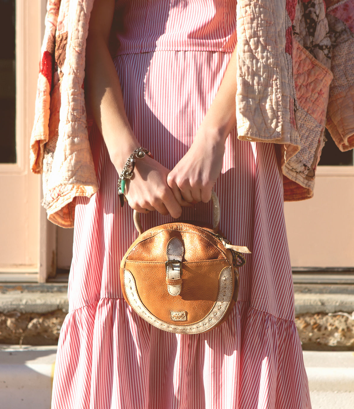 A woman in a pink dress holding a Bed Stu Arenfield bag.