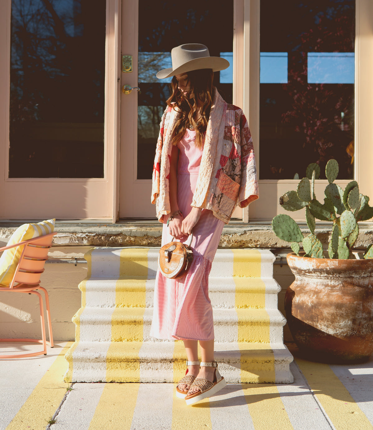 A woman wearing a pink dress, hat and holding a Bed Stu Arenfield.