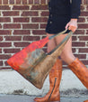 A woman in a pair of Bed Stu cowboy boots carrying an Ariel bag.