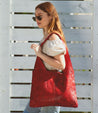 A woman carrying a red leather Ariel hobo bag by Bed Stu.