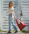 A woman wearing jeans and a red Bed Stu tote bag.