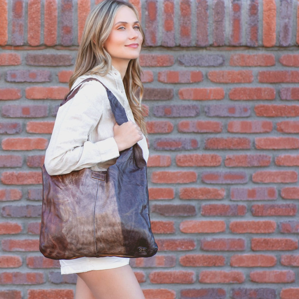 A woman wearing white shorts and a brown leather Bed Stu Ariel tote bag.