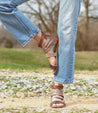 A woman in Bed Stu jeans and Artemis sandals standing on a dirt road.