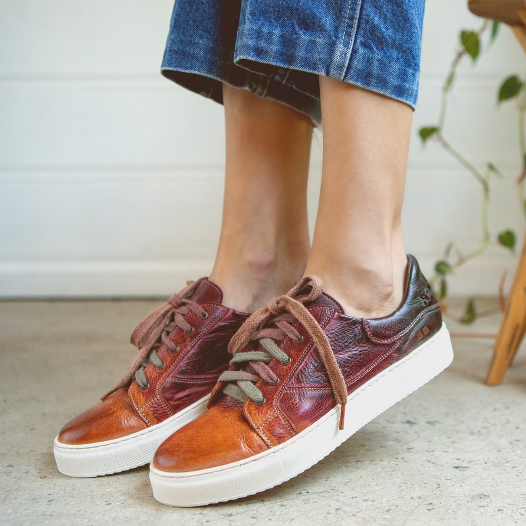 A woman wearing a pair of Bed Stu Azeli burgundy leather sneakers.