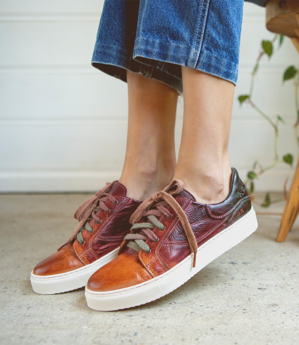 A woman wearing a pair of Bed Stu Azeli burgundy leather sneakers.