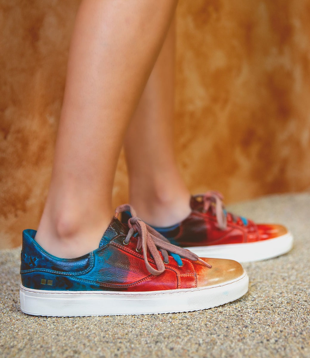A woman wearing a pair of Bed Stu Azeli sneakers with colorful paint on them.