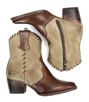 The Baila II ankle cowboy boots by Bed Stu are designed in a brown and beige combination, featuring a side zipper. They are decorated with whipstitch accents and intricate stitching details, showcasing their western-inspired style against a white background.