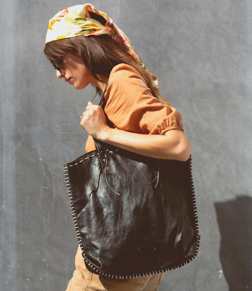 A woman carrying a black leather Bed Stu Barra tote bag.