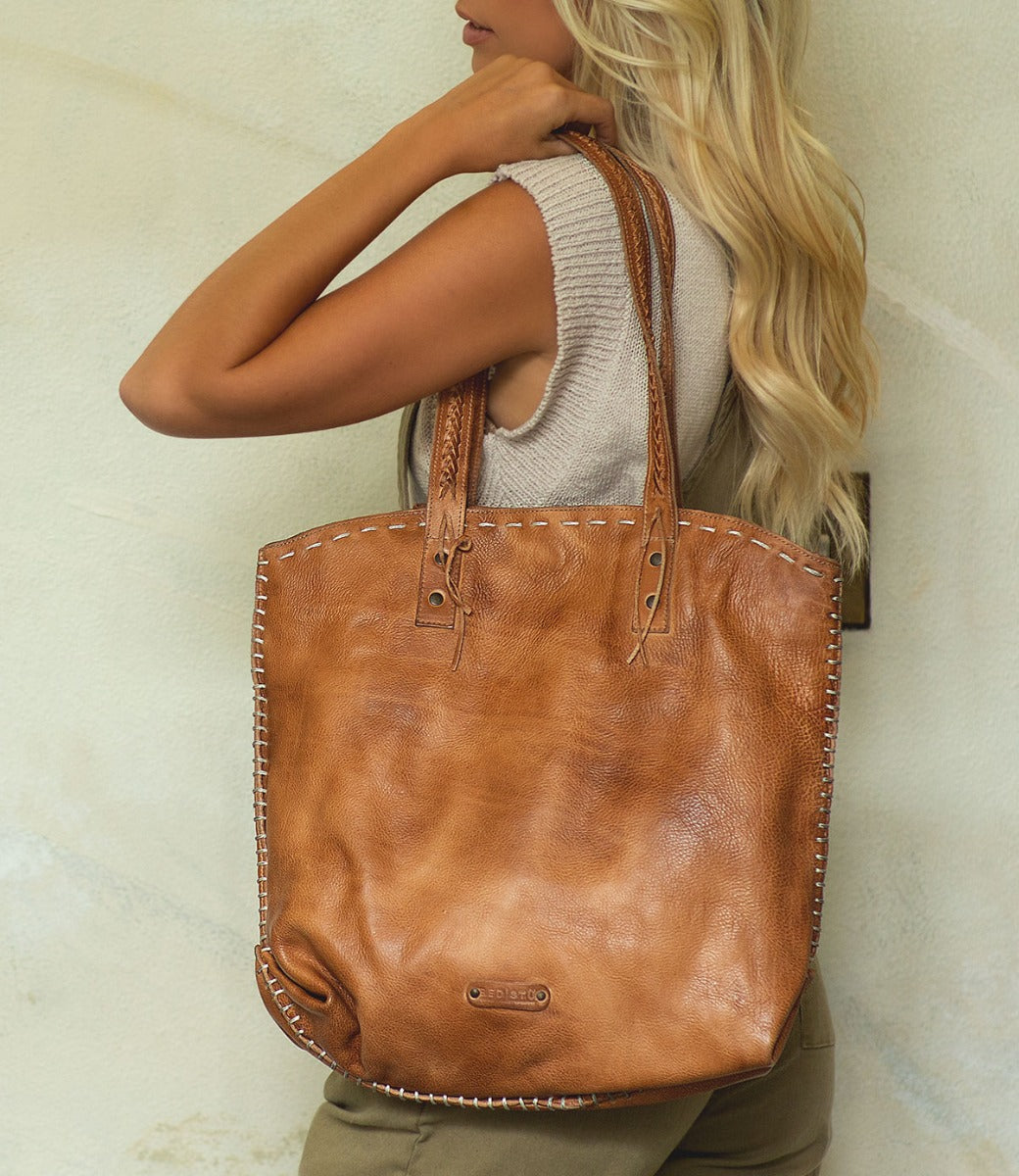 A blonde woman holding a Barra leather tote bag by Bed Stu.