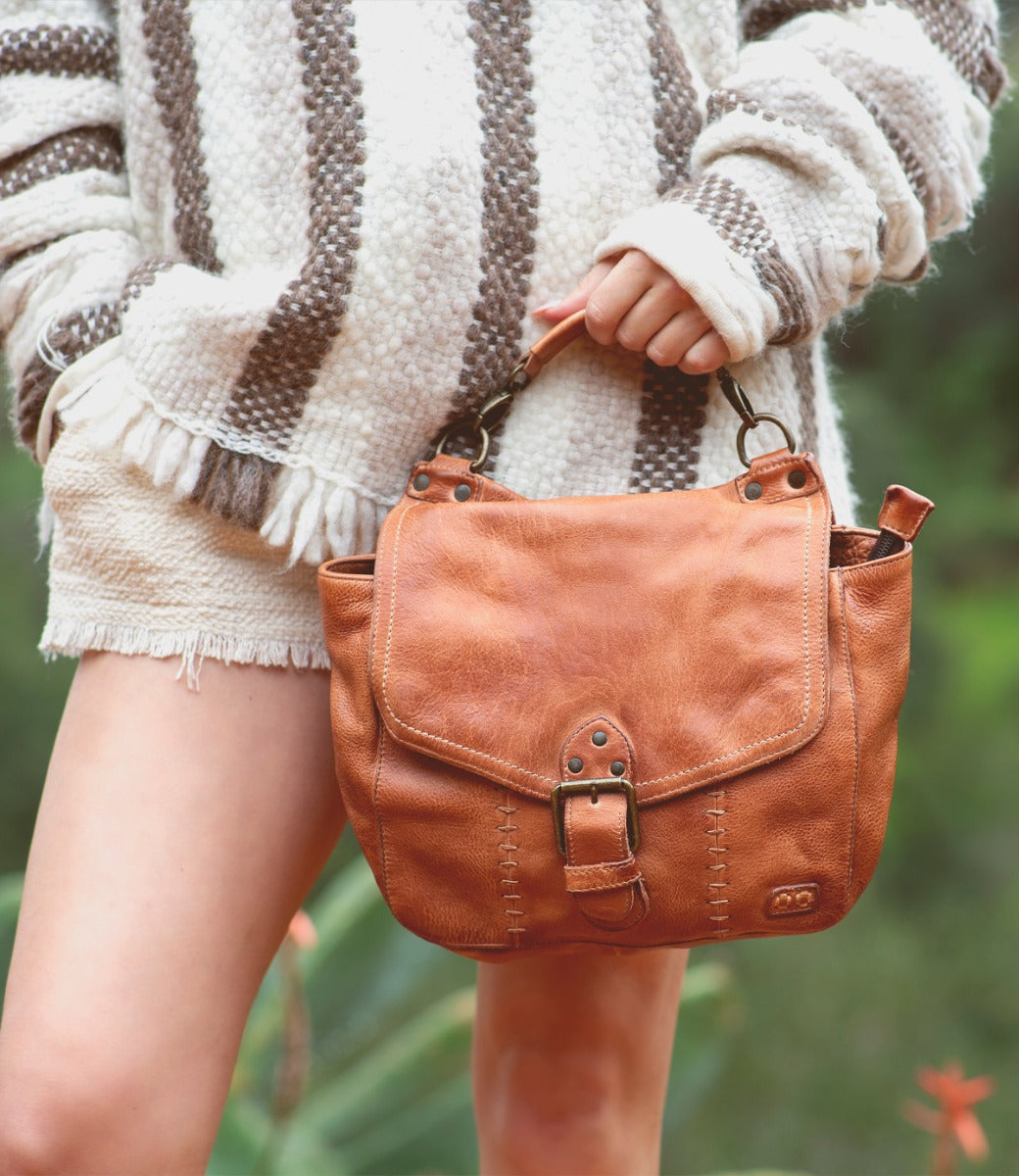 A woman holding a brown Bed Stu Bathsheba handbag.