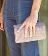 A woman is holding a Bayshore clutch bag by Bed Stu.