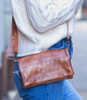A woman wearing jeans and a Bed Stu Bayshore tan leather crossbody bag.