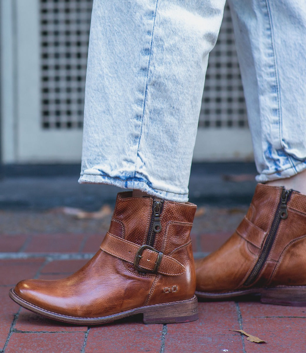 A woman wearing a pair of Bed Stu Becca tan leather boots.
