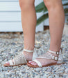 A woman's feet in a pair of Bed Stu Bellatrix II white sandals.