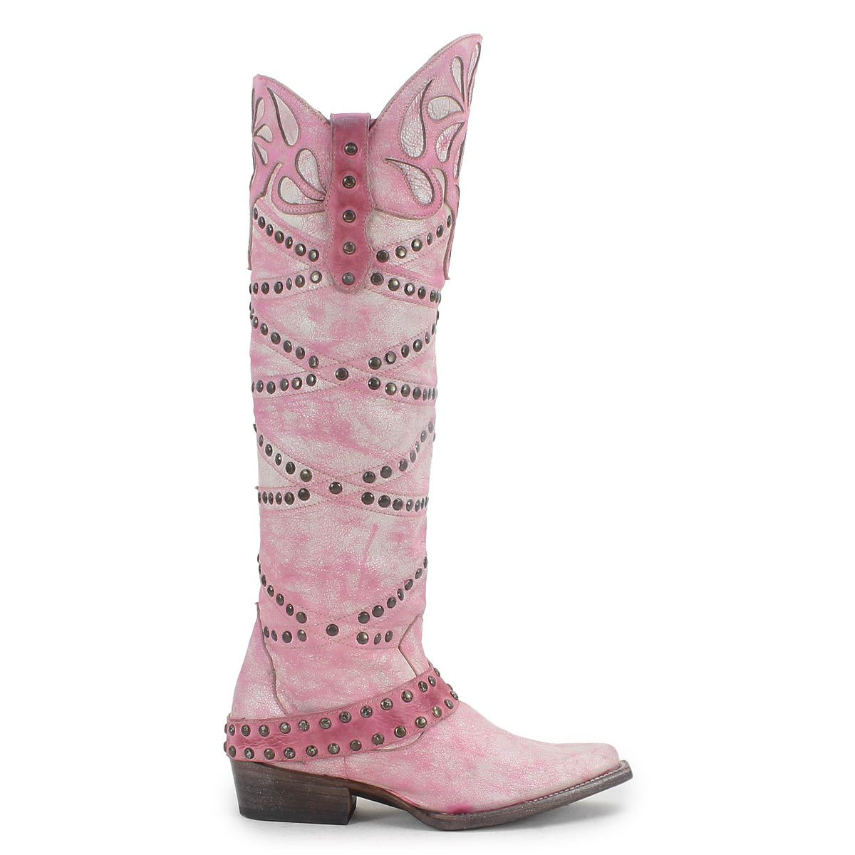 The Bed Stu "Betting" boot in pink showcases a pointed toe, mid-height heel, and features decorative cut-out patterns with metal studs. Crafted from vegetable-tanned leather, it includes a stylish harness strap for added flair.