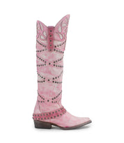 The Bed Stu "Betting" boot in pink showcases a pointed toe, mid-height heel, and features decorative cut-out patterns with metal studs. Crafted from vegetable-tanned leather, it includes a stylish harness strap for added flair.