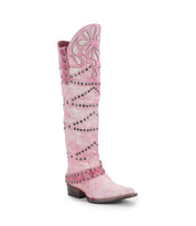 The Bed Stu "Betting" boot is a tall pink Western-style boot with floral cutouts, studded details, and a low heel made from vegetable-tanned leather.