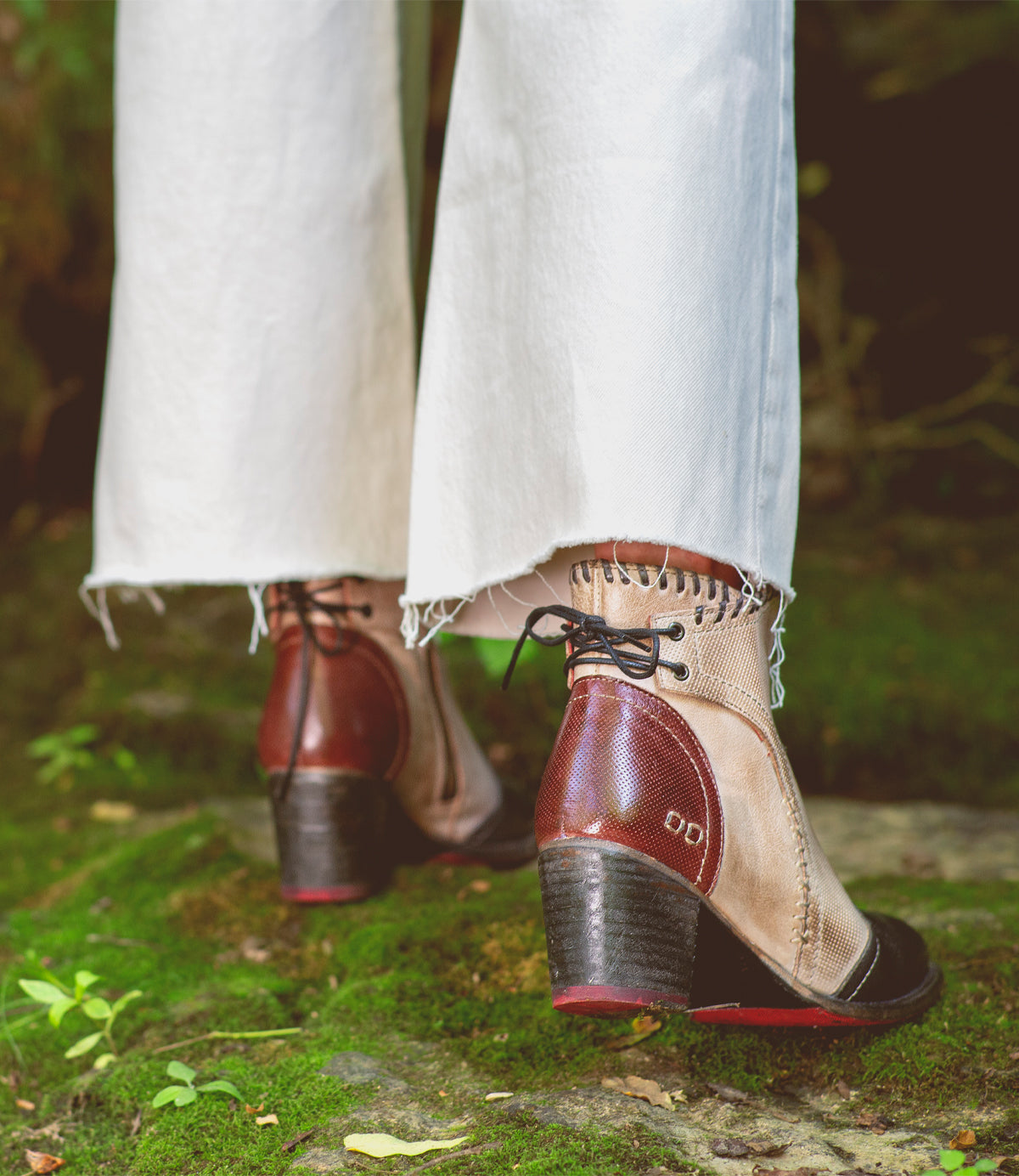 A woman's feet are wearing Bed Stu Bia sandals standing on a rock in the woods.