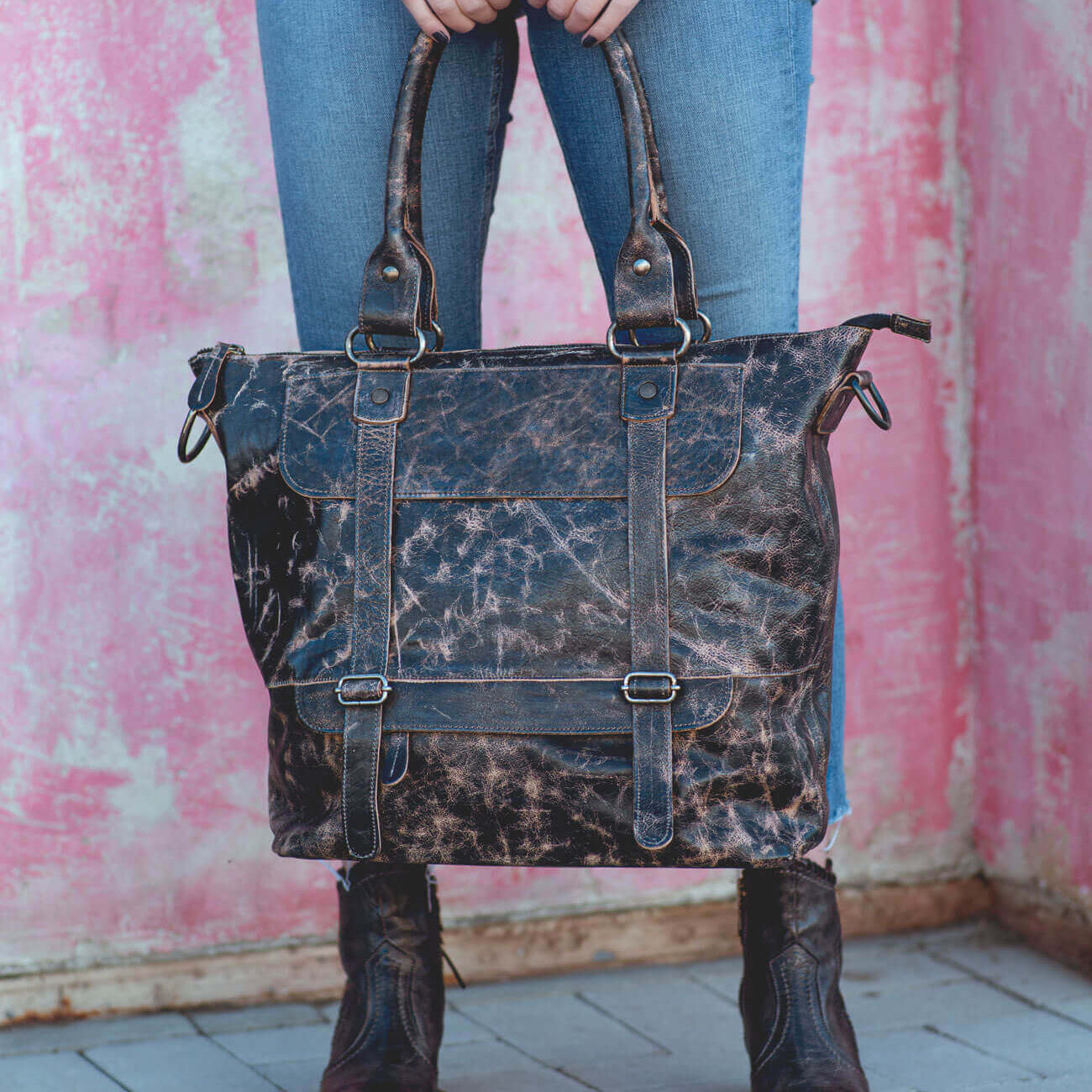 A woman holding a Bed Stu black leather tote bag.