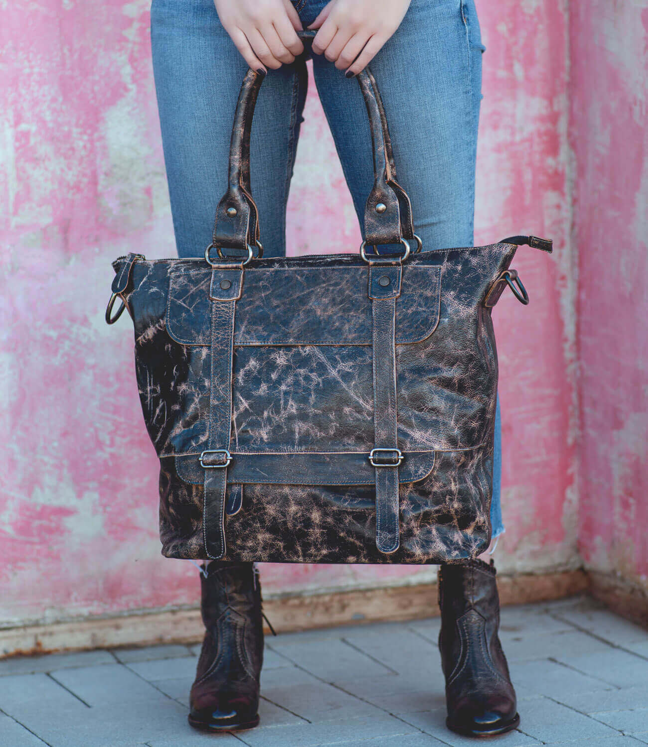 A woman holding a Bed Stu black leather tote bag.