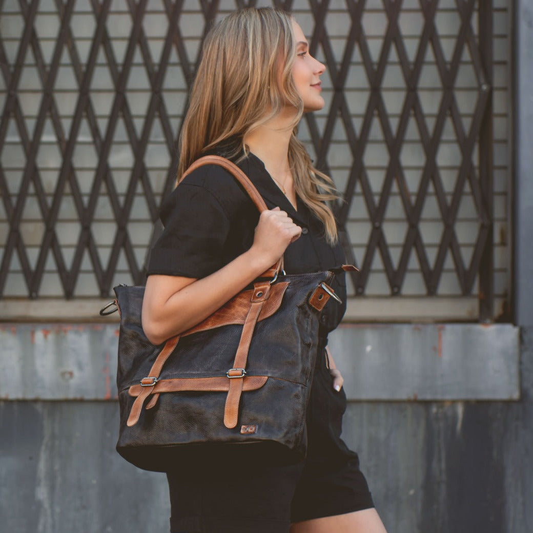 A woman wearing black shorts and a black Bed Stu Big Fork leather bag.