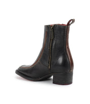 The Bed Stu Bitsy is a black hand-finished leather ankle boot with a side zipper, brown trim, pull tab, and stacked wooden block heel, shown on a white background.