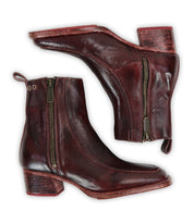 The Bed Stu Bitsy is a pair of brown hand-finished leather ankle boots with side zippers and low stacked wooden heels, shown from the side and bottom views.