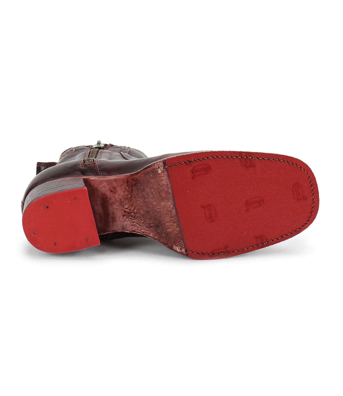 The Bed Stu Bitsy is a brown leather ankle boot shown from the bottom, with a worn red sole, visible stitching, subtle patterns, and a stacked wooden heel made from hand-finished leather.