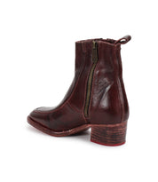 The Bitsy by Bed Stu is a dark brown, hand-finished leather ankle boot with a side zipper and low stacked wooden heel, shown from the rear side.