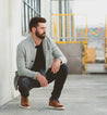 A man crouching down in front of a Bowery II building Bed Stu.