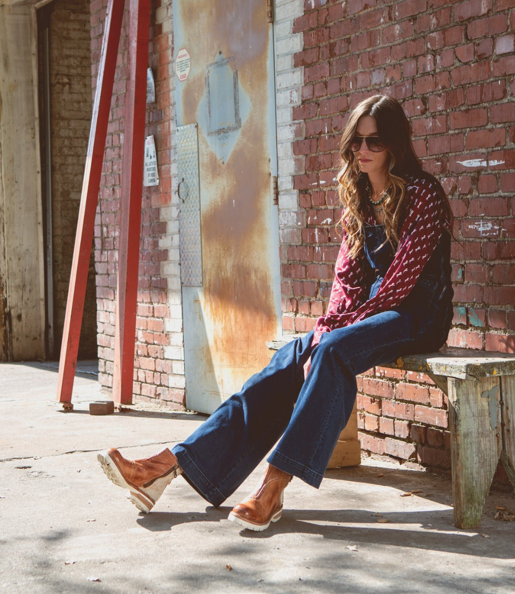 A woman in Brianna boots sitting on a bench.