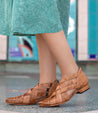 A woman wearing Brittany shoes by Bed Stu and a green skirt.