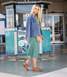 A blonde woman wearing a Bed Stu denim jacket and a Bed Stu midi dress.