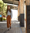 A woman wearing a Brittany shirt printed with stripes and Bed Stu brown pants.