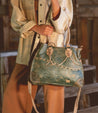 A woman carrying a teal Bed Stu Bruna leather bag.