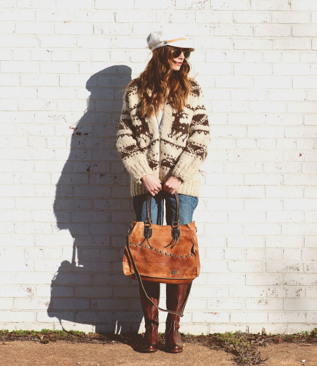 A woman holding a Bruna bag in front of a brick wall, made by Bed Stu.