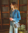 A woman wearing Buffy jeans and a Bed Stu denim jacket standing in a barn.